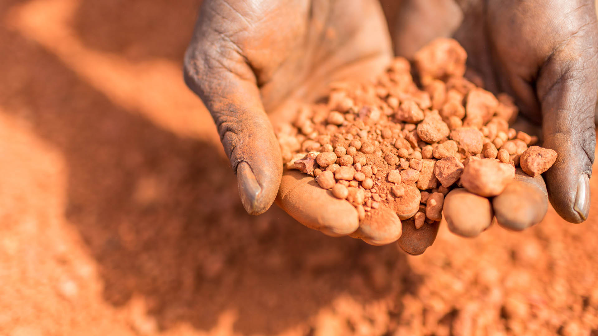 Hands scooping up red soil